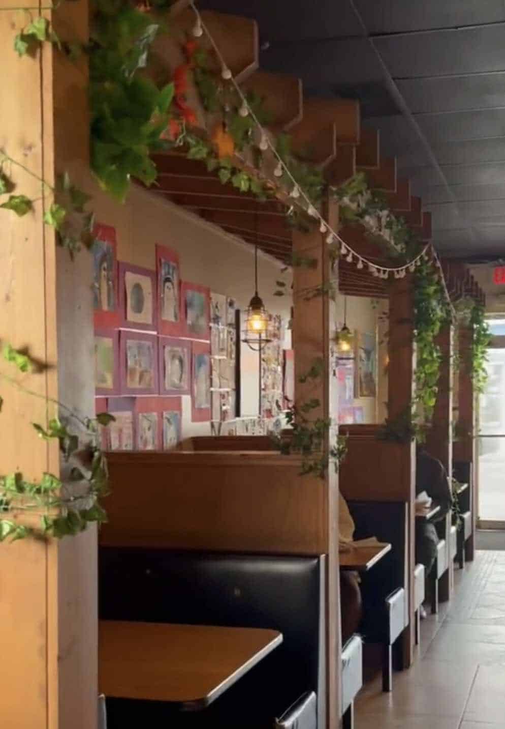 The inside of The Horn cafe showing wood tables with greenery and lights.