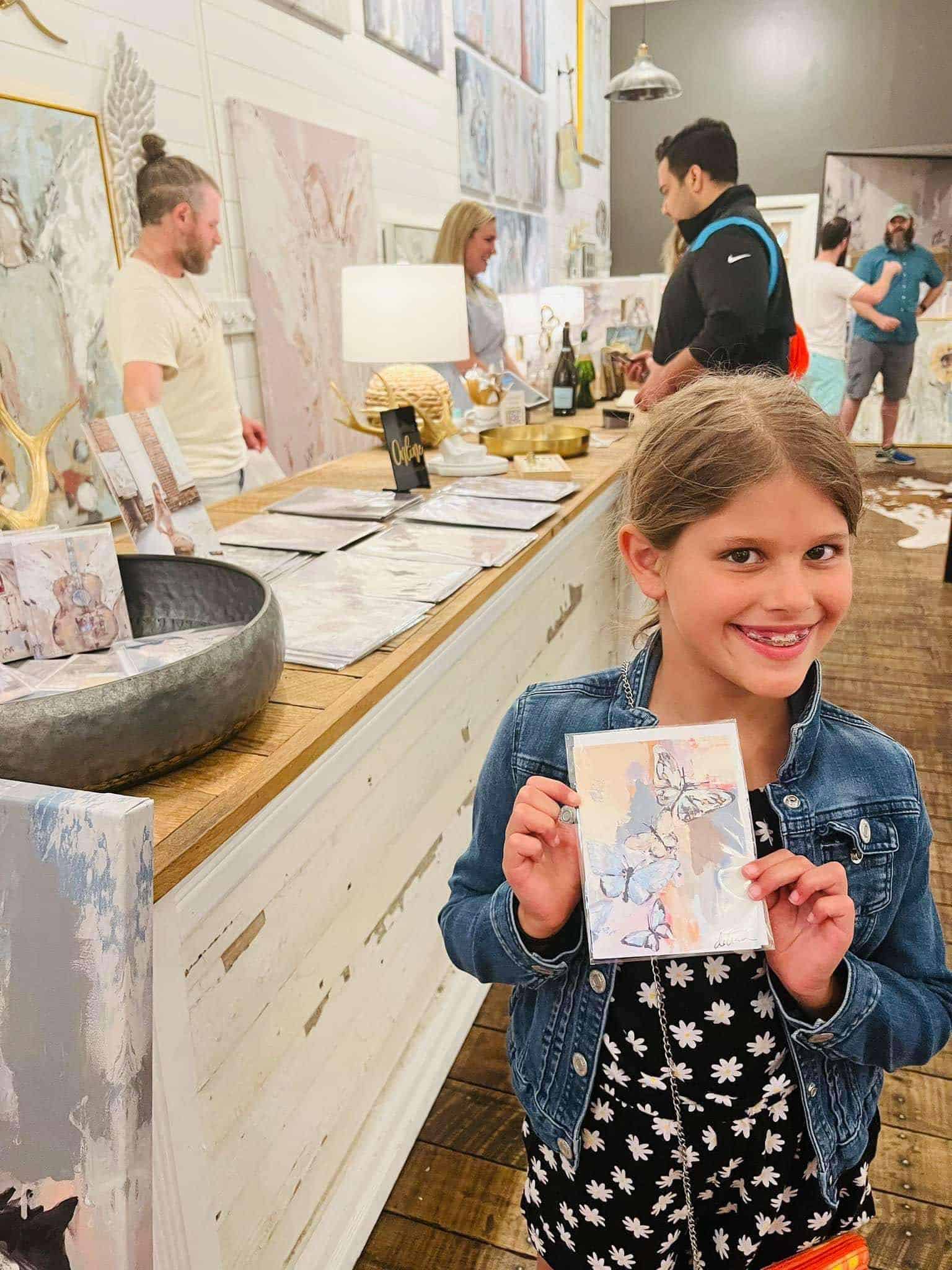 Little girl holding a small painting at the art crawl.