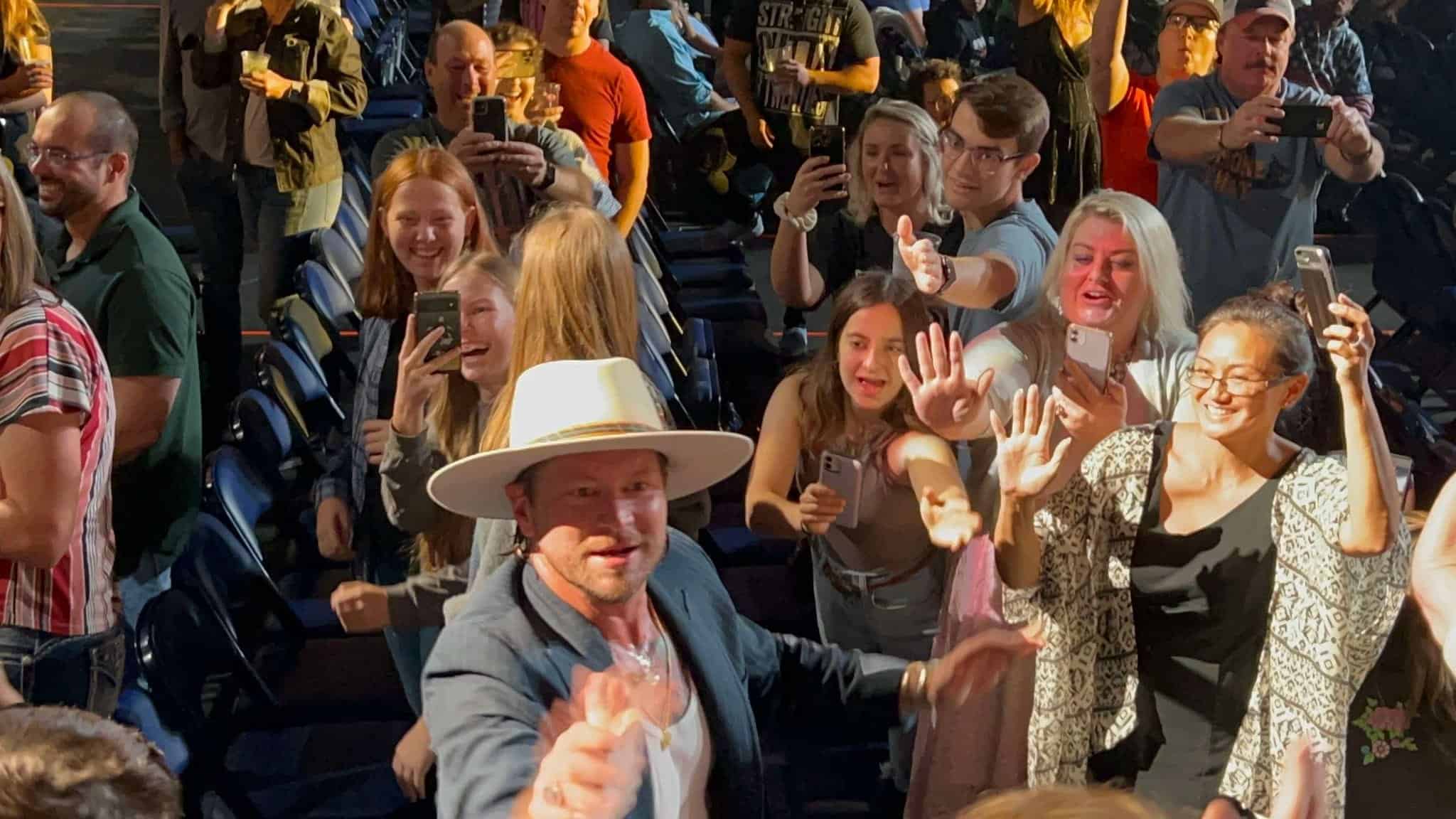 Singer greets crowd and shakes hands with people.