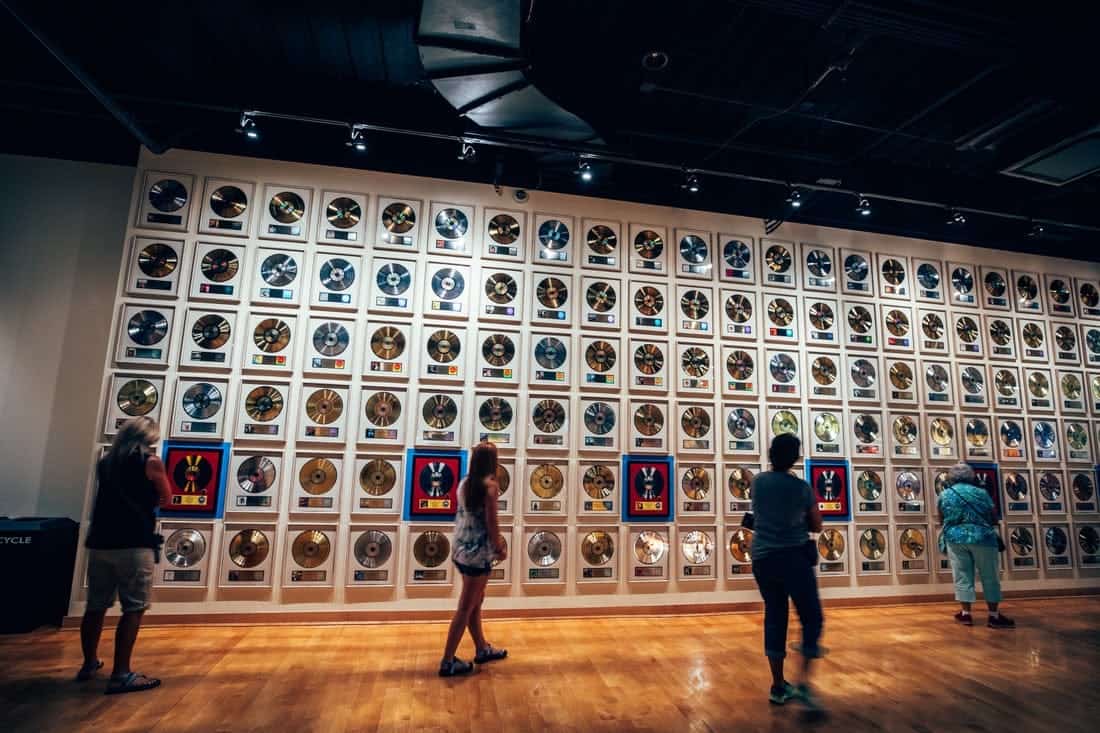 People looking at a wall full of albums at the Country Music Hall of Fame.