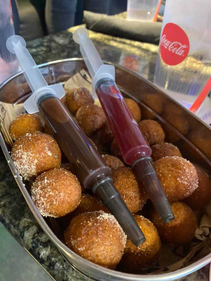 Container of donuts with two syringe fillings that people can insert into their donuts.
