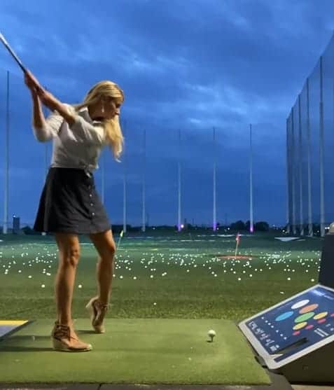 Girl swinging golf club at Top Golf.