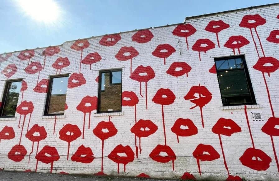 Art mural of a white wall and red lips on the side of a building in downtown Nashville.