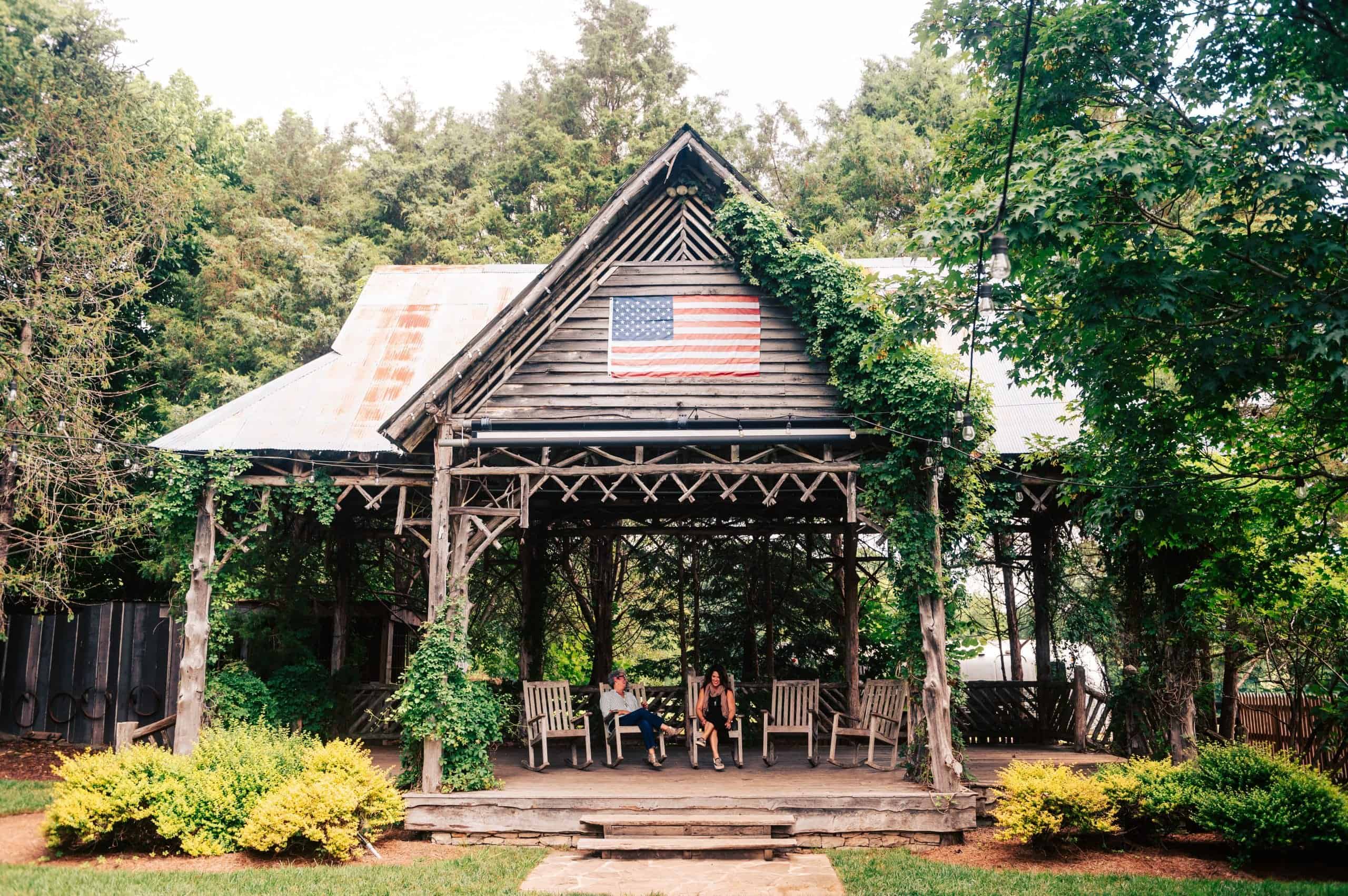 Old, wooden gazeebo with an American flag hanging from it. 