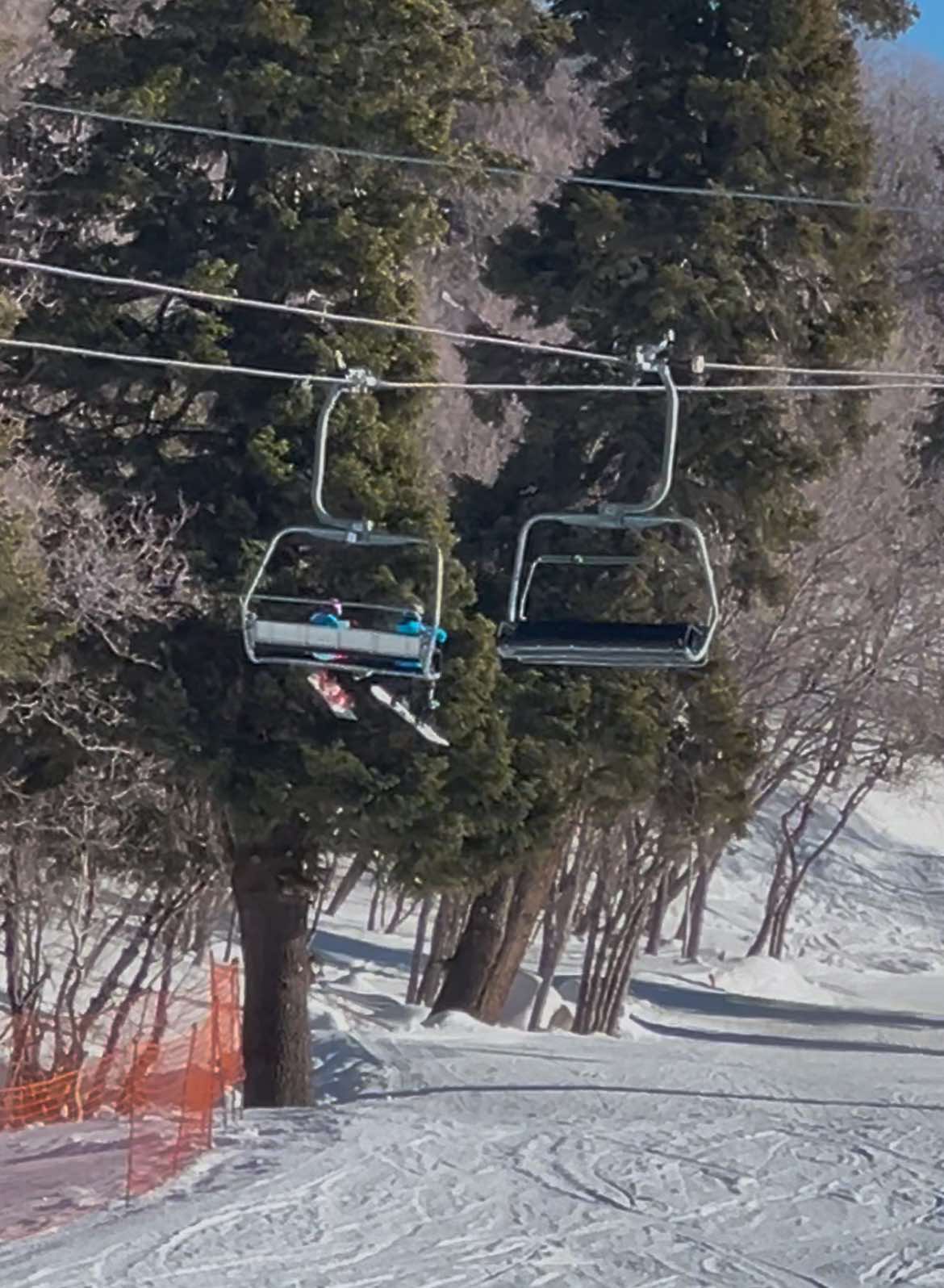 Two kids riding the Little Cat chairlift by themselves while on their family snowboarding trip to Snowbasin Ski Resort.