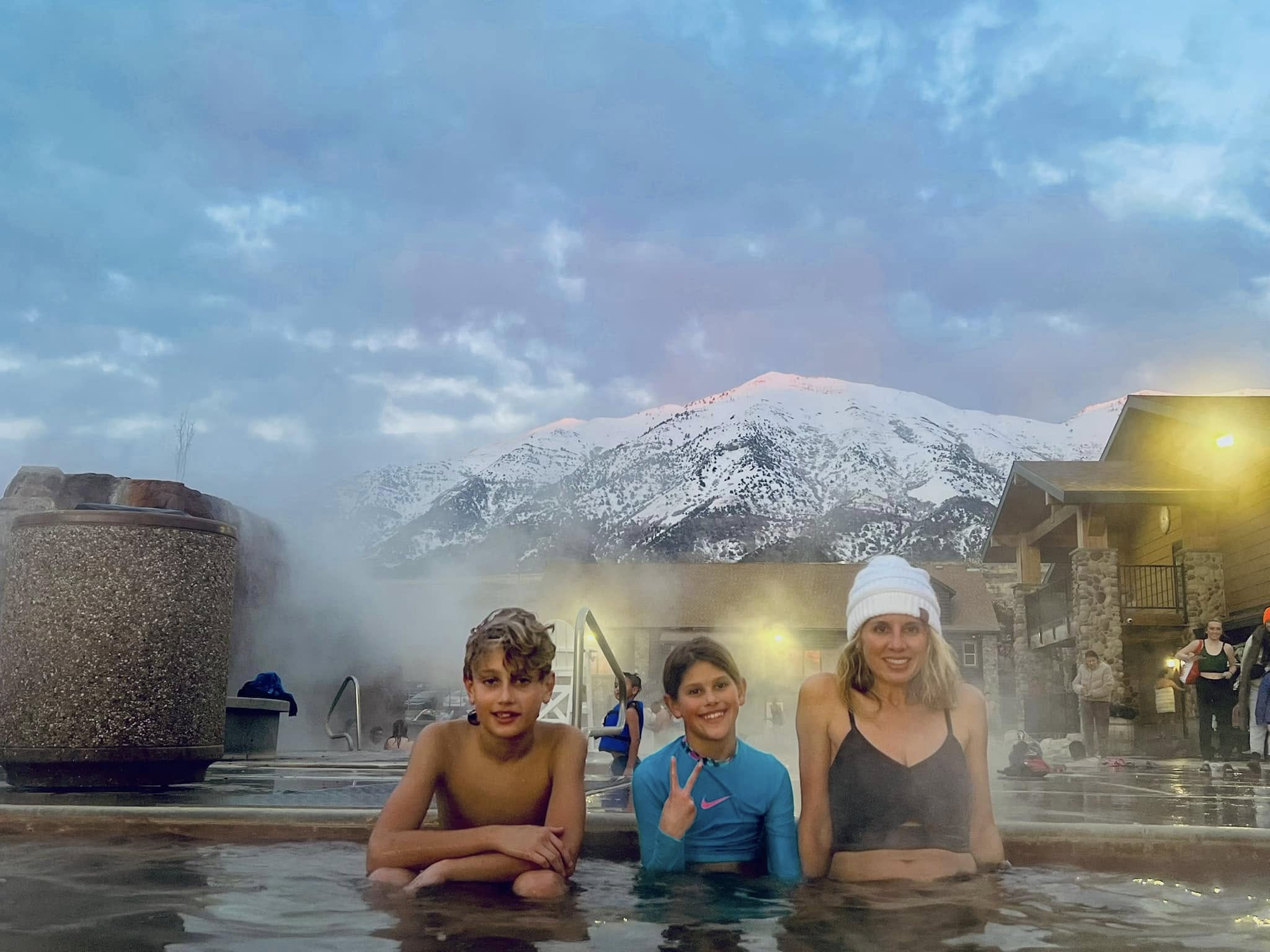 A mom and kids in the Crystal Hot Springs for their apres ski during their family snowboarding trip to Snowbasin Ski Resort in Utah.