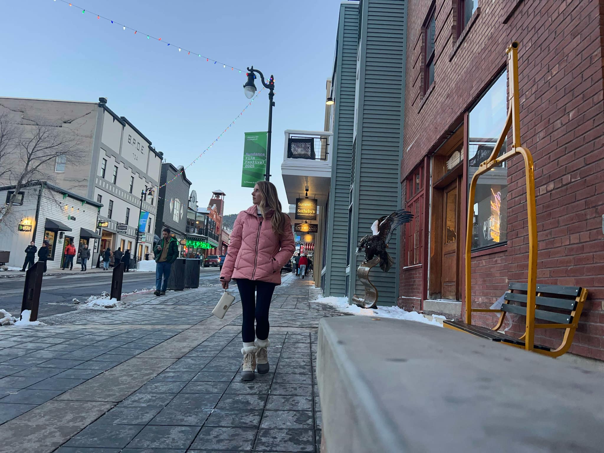 A girl in a pink coat walking the streets of Park City.