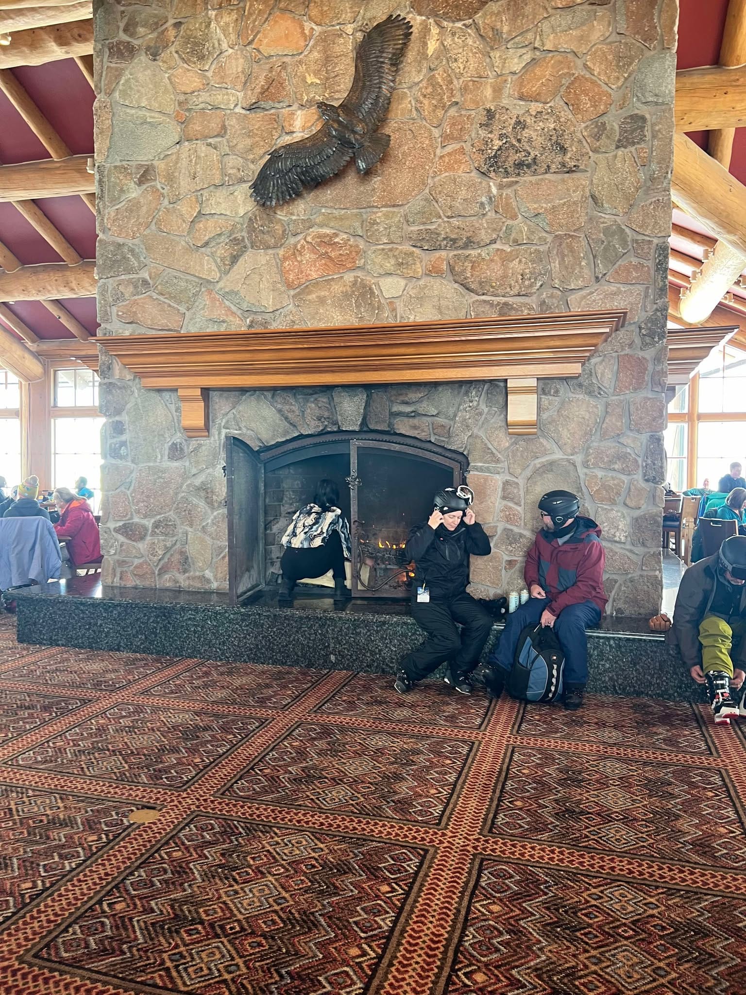 A lady puts more logs on the fire in Needle's Lodge at Snowbasin.