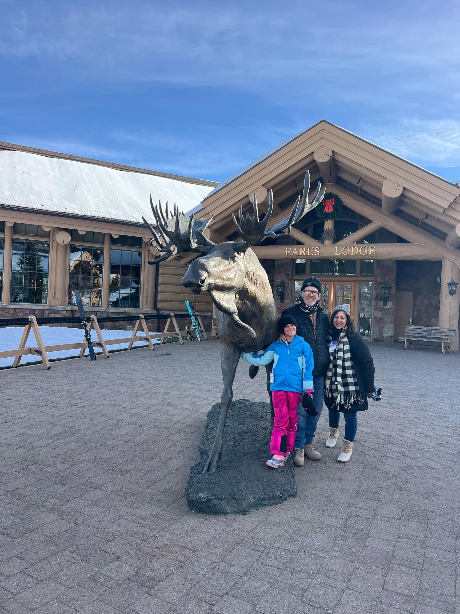 A little girl poses with her grandparents at the big elk in front of Earl's Lodge.