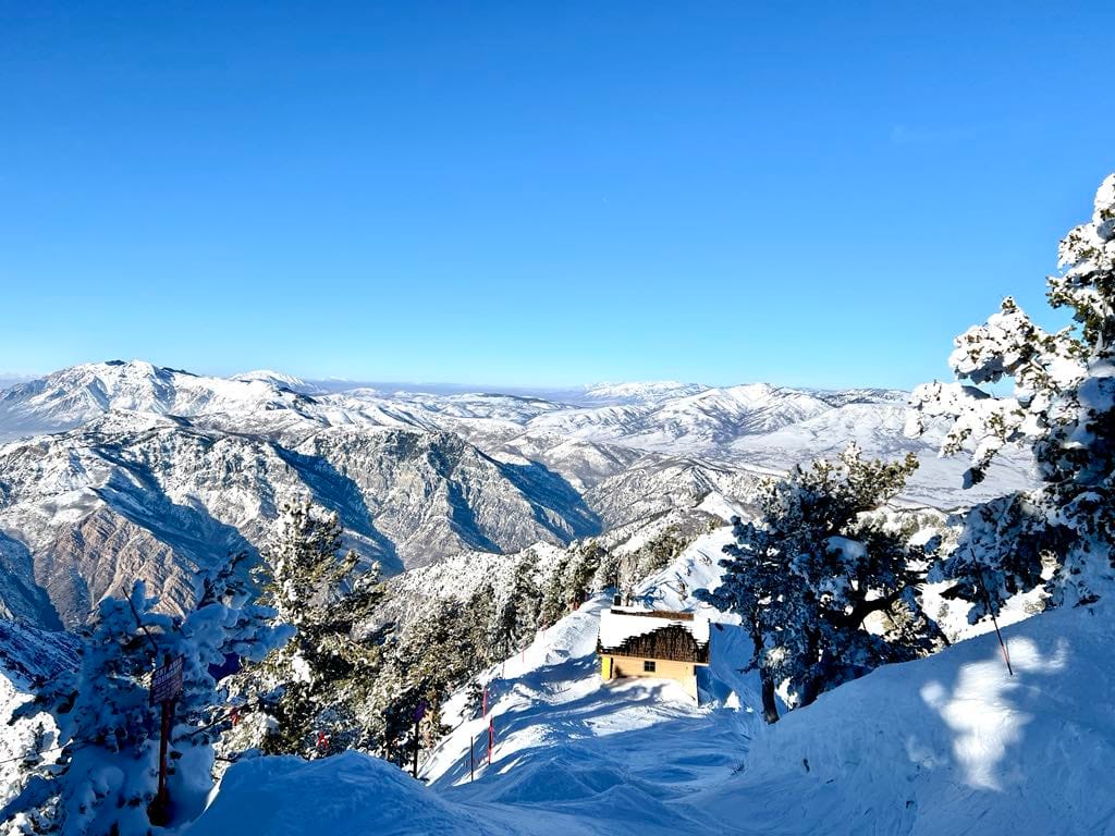 Incredible views from the top of the tram at Snowbasin's John Paul Lodge. There is a little hut and everything is covered in snow.