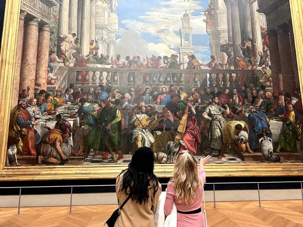 Two girls admiring a massive painting at the Louvre in Paris.