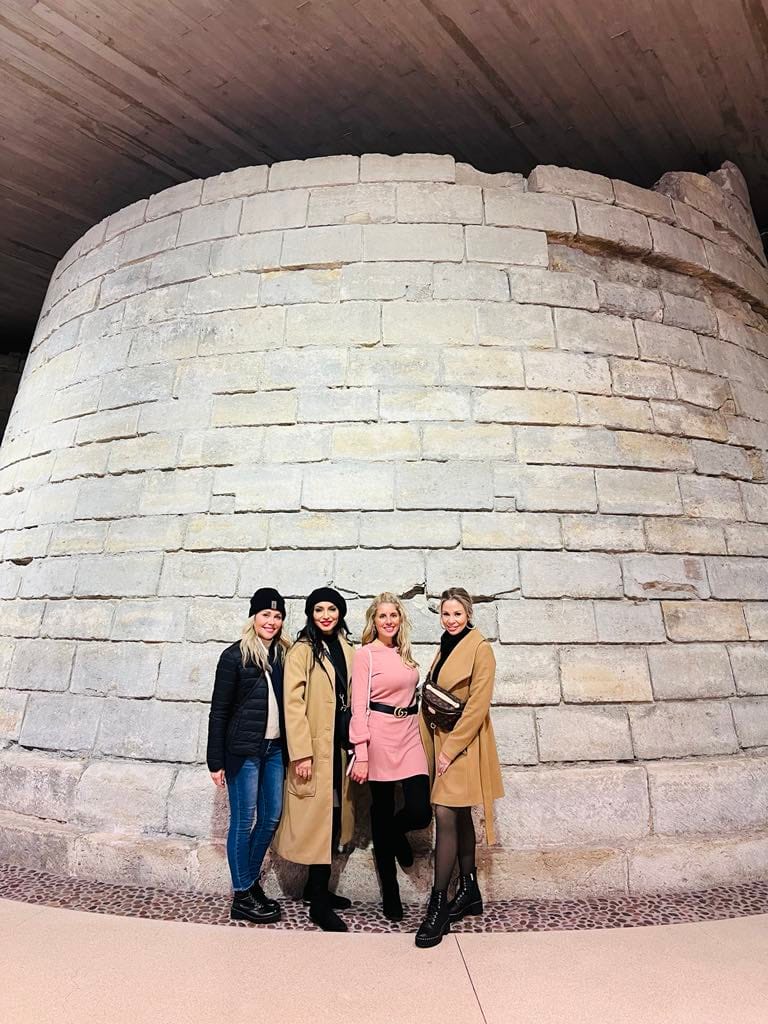 Four girls standing at the pillar of the Louvre for this free things to do in Paris photo.