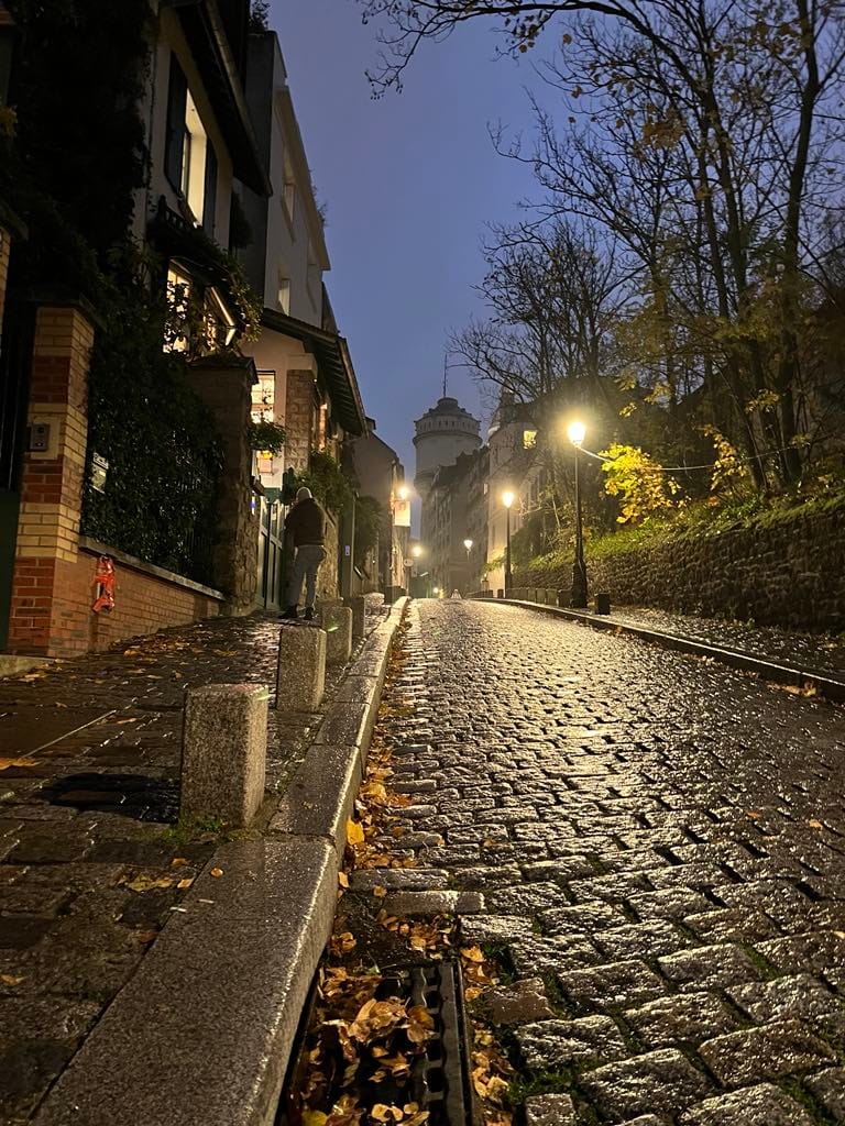 A picture of Montmartre at night showing the cobblestone street incline.