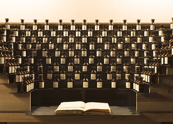 This photo is a black and white photo featuring dozens of jars of perfume.