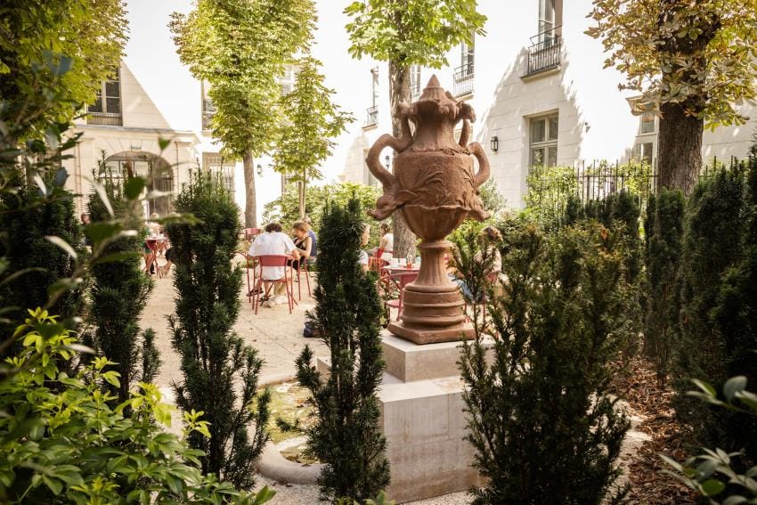 A picture of the Victor Hugo Cafe courtyard where people are eating.