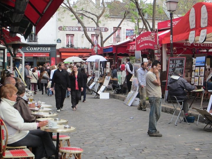 Another picture of the square of Montmartre during a busy season. Lots of people sitting at the cafes and walking around looking at the artwork.