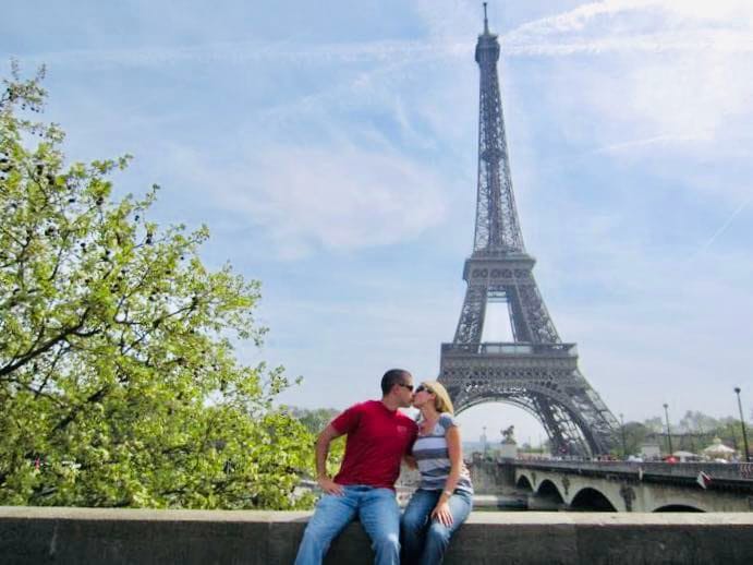 Guy and girl kissing in front of the Eiffel Tower in Paris.