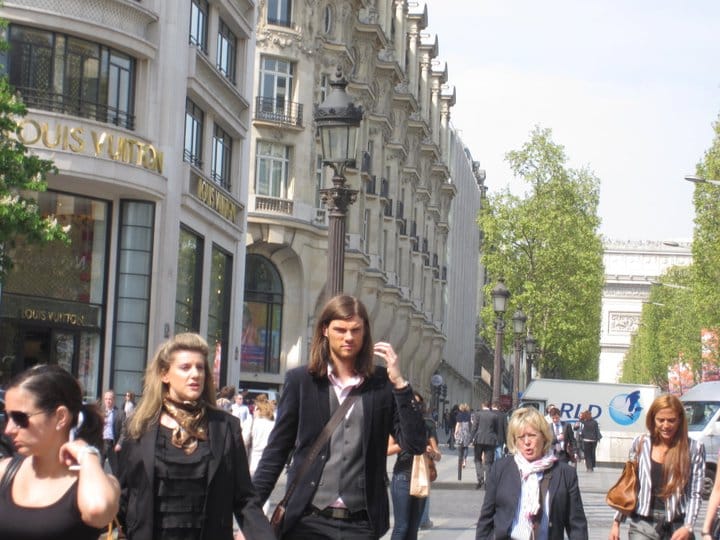 Lots of people walking down Champs Elysees, two of them who look like models. 