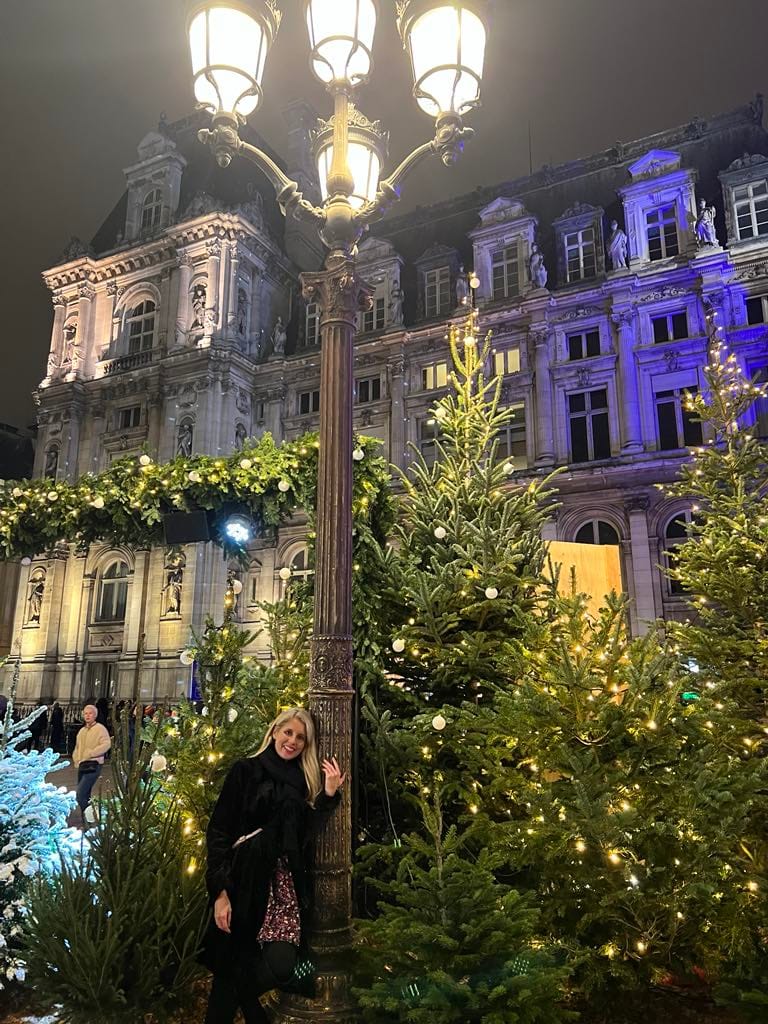 This free things to do in Paris picture features a girl leaning on a lamp post in front of the beautiful city hall.