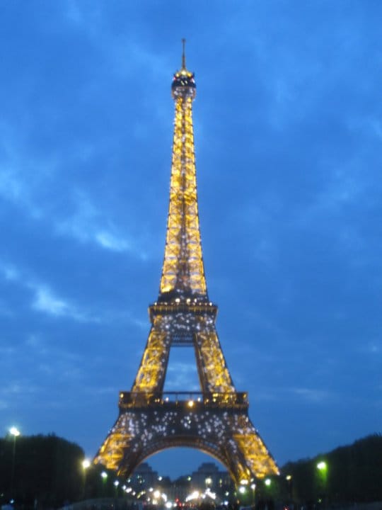 The Eiffel Tower in Paris all lit up against a bright blue night sky.