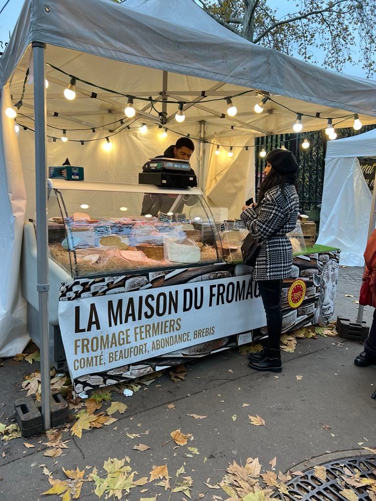 Girl shopping at a local cheese vendor at a free market in Paris.