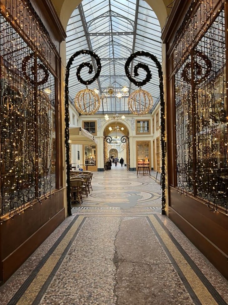 This photo of free things to do in Paris features one of the Passages shopping centers. It is decorated with golden lights and iron with a glass dome over top.