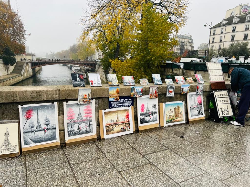 An art vendor sets up his art across a bridge over the Seine River for this free things to do in Paris picture.