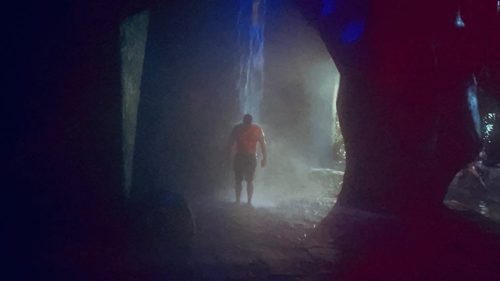 Man inside of a hot springs cave having the hot waterfall hit his back during his Costa Rica with kids trip.