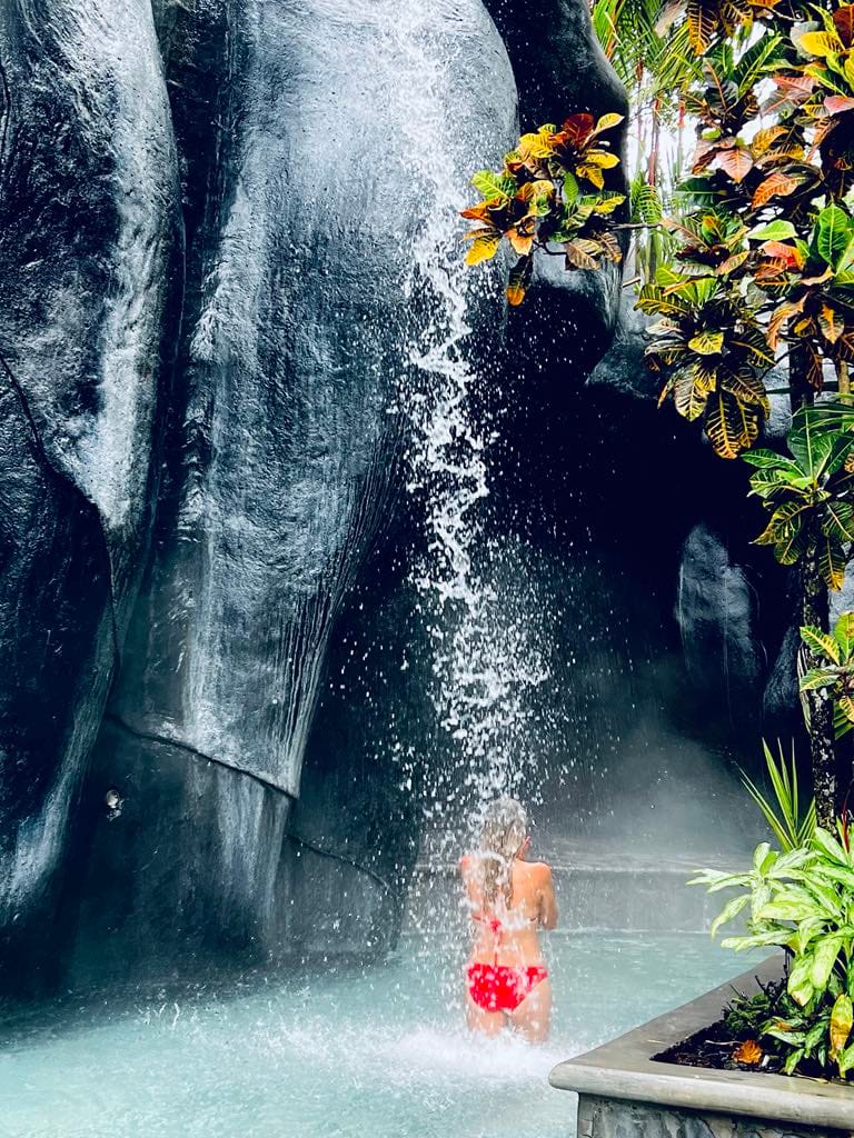 A mom under the waterfall at the Baldi Hot Springs Resort while on her Costa Rica with Kids trip.