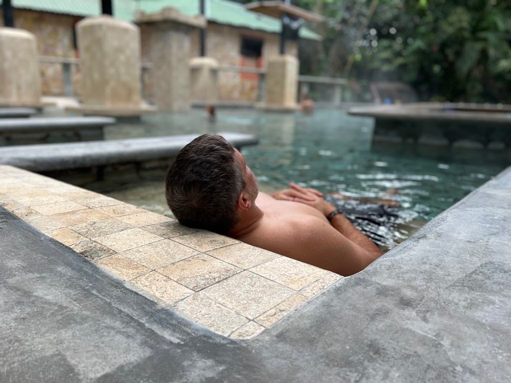 Man relaxing on a hot stone in the hot spring pool in Costa Rica.
