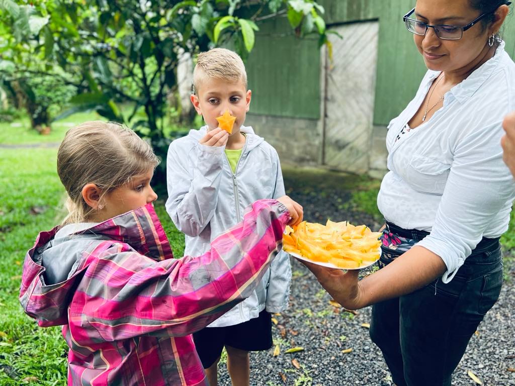 Two kids trying new fruits at a chocolate farm while on a Costa Rica with Kids trip.