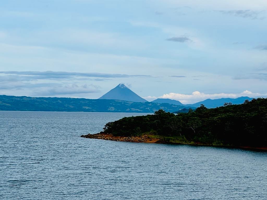A view of the La Fortuna volcano with a lake in front of it.