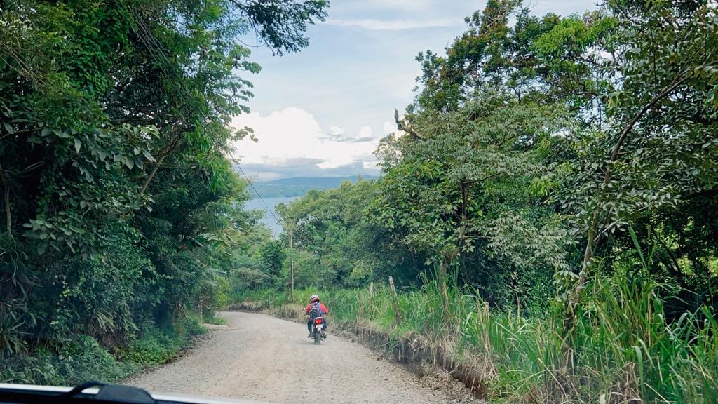 Two men riding a moped through Costa Rica back roads.
