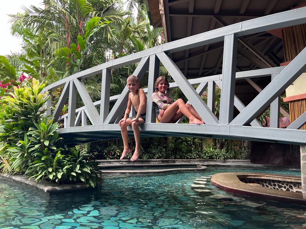 Two kids hanging out on a bridge over a hot spring at the Baldi Resort in Costa Rica.