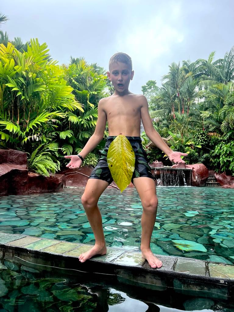 A preteen boy trying to be funny with a huge banana leaf over his shorts at the Baldi Resort in Costa Rica.