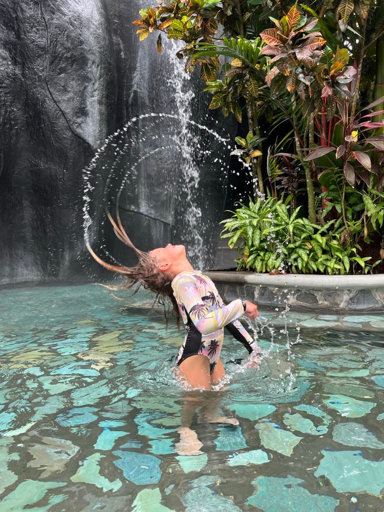 A little girl doing a hair flip in the hot spring at Baldi Resort in Costa Rica.