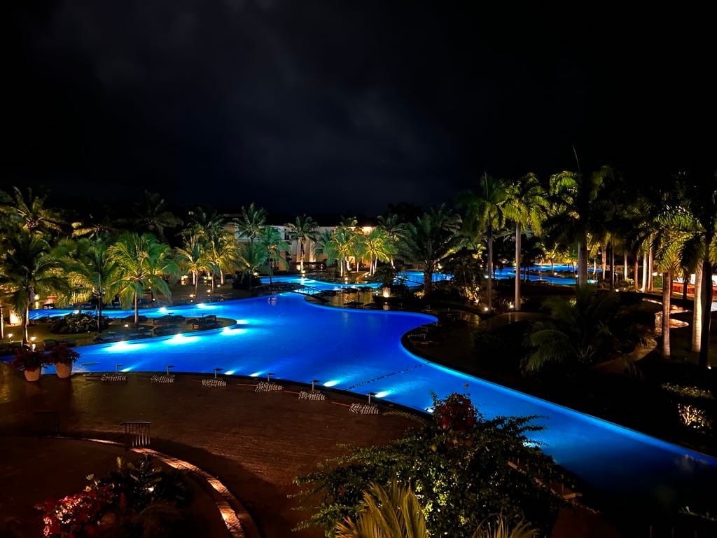 A view of the pool at night. The bright blue pool lights up and contrasts beautifully against the dark night sky.