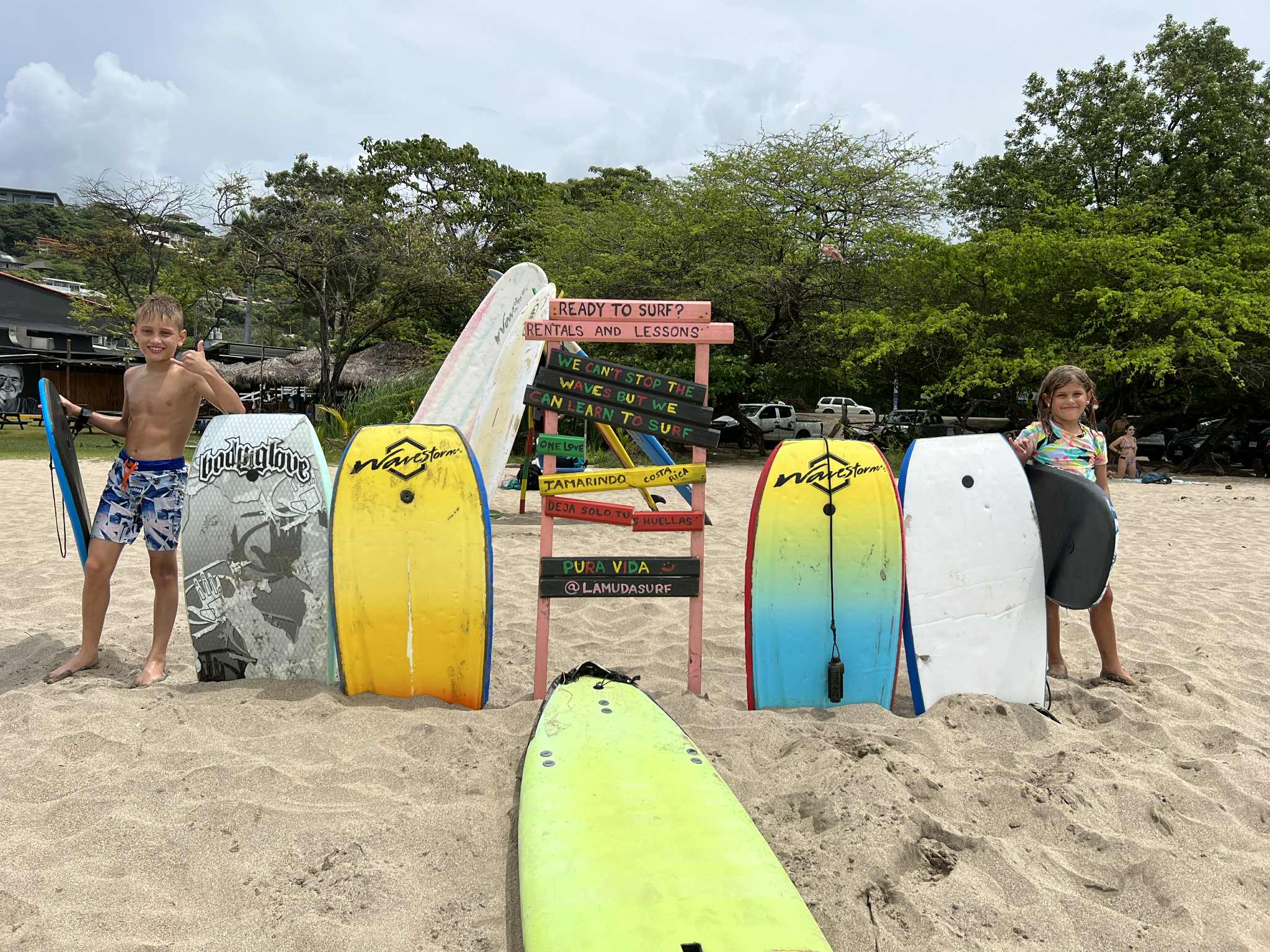 Two kids standing next to a surfing sign in Costa Rica.