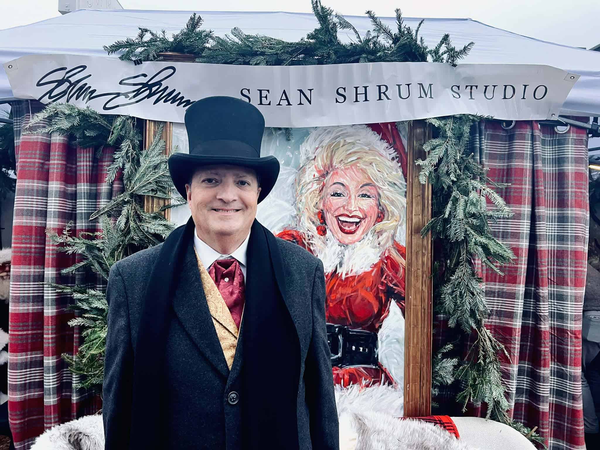 A man dressed in 1800s clothes with a top hat at the Dickens of a Christmas festival.