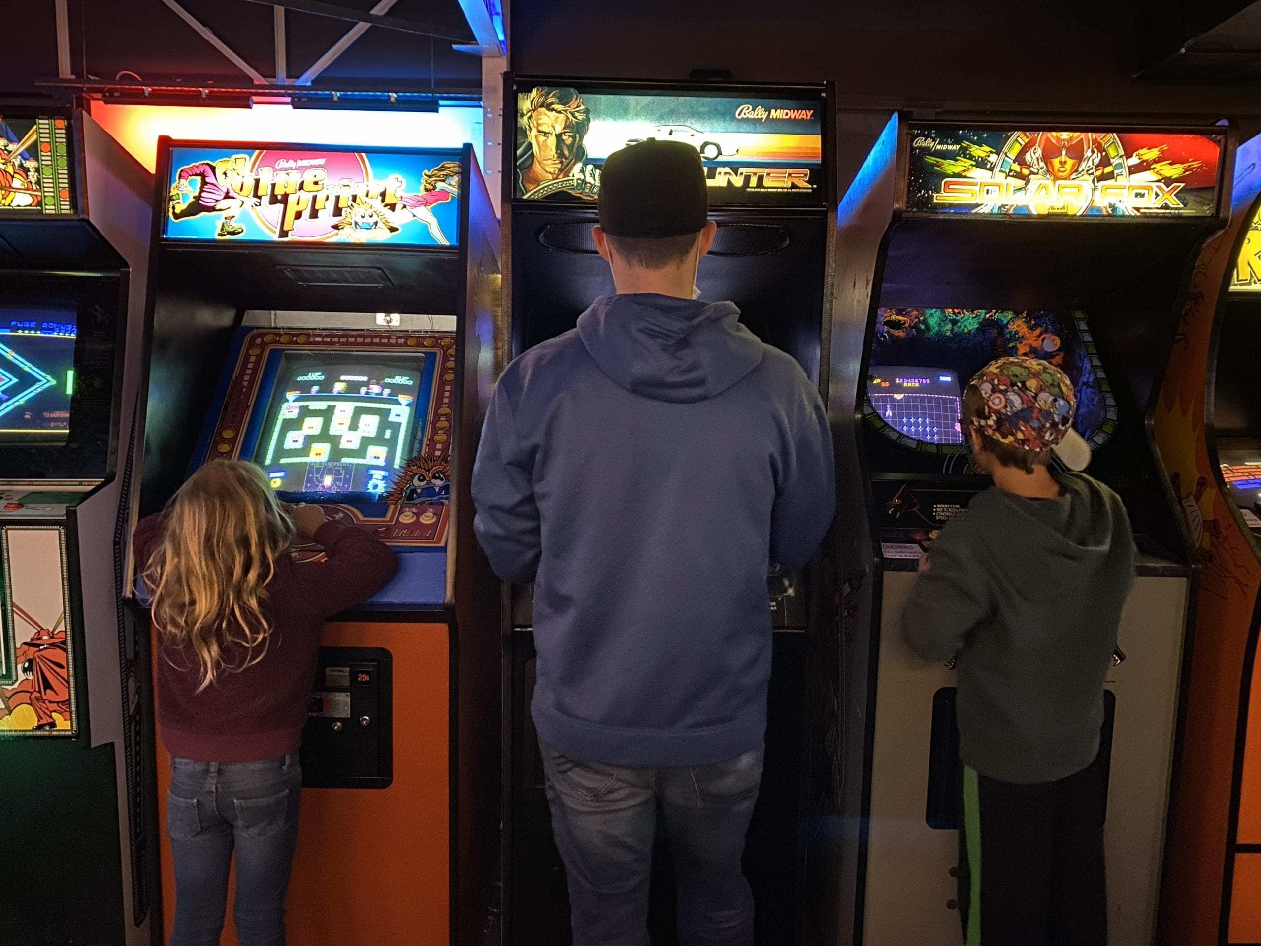 A man and two kids playing old school style games at The Game Terminal.
