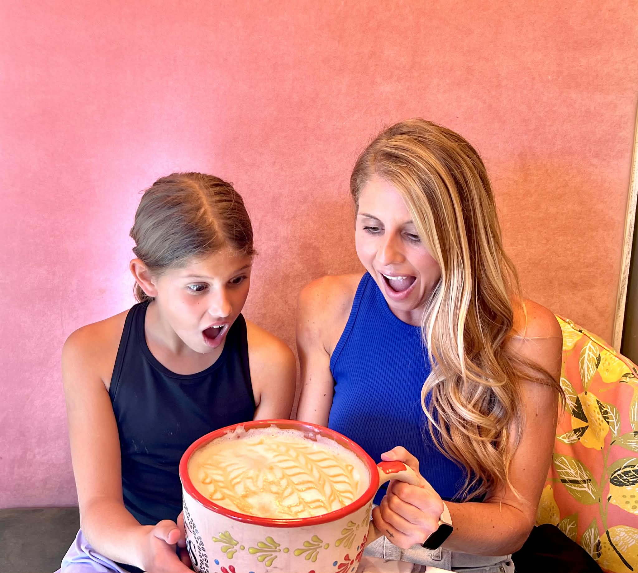 A mom and daughter looking surprised at their huge coffee,