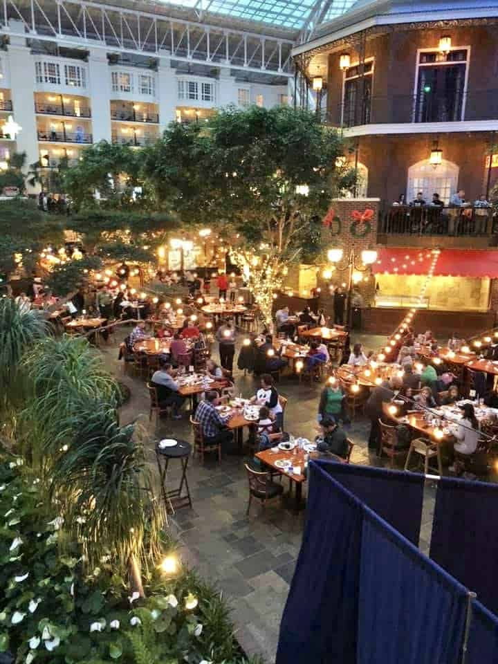 People eating at a restaurant that is made to look like an outdoor bistro while inside the Gaylord Opryland Hotel.