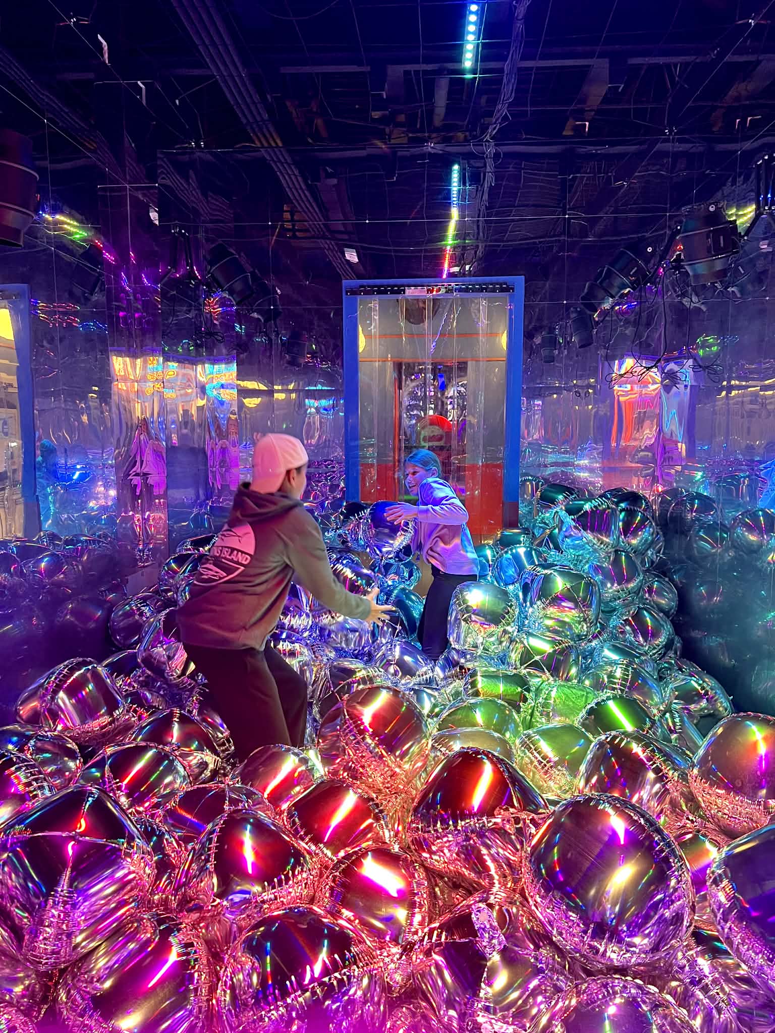 A room full of balloons and neon lights at Play Playground. The kids are throwing balloons at each other.
