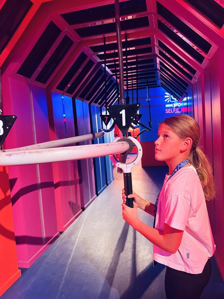 A little girl playing a game at Play Playground in Nashville where she has to move a wrench around obstacles as fast as she can.