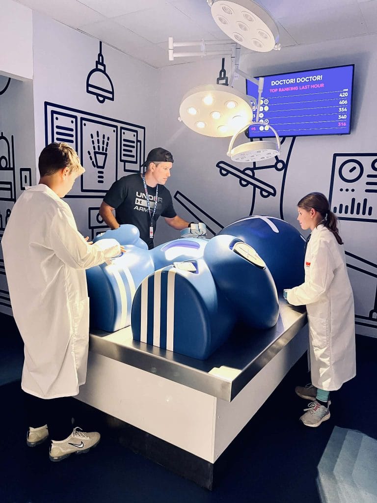 A family with kids playing a massive Operation style game at Play Playground in Nashville. The kids have doctor suits on.