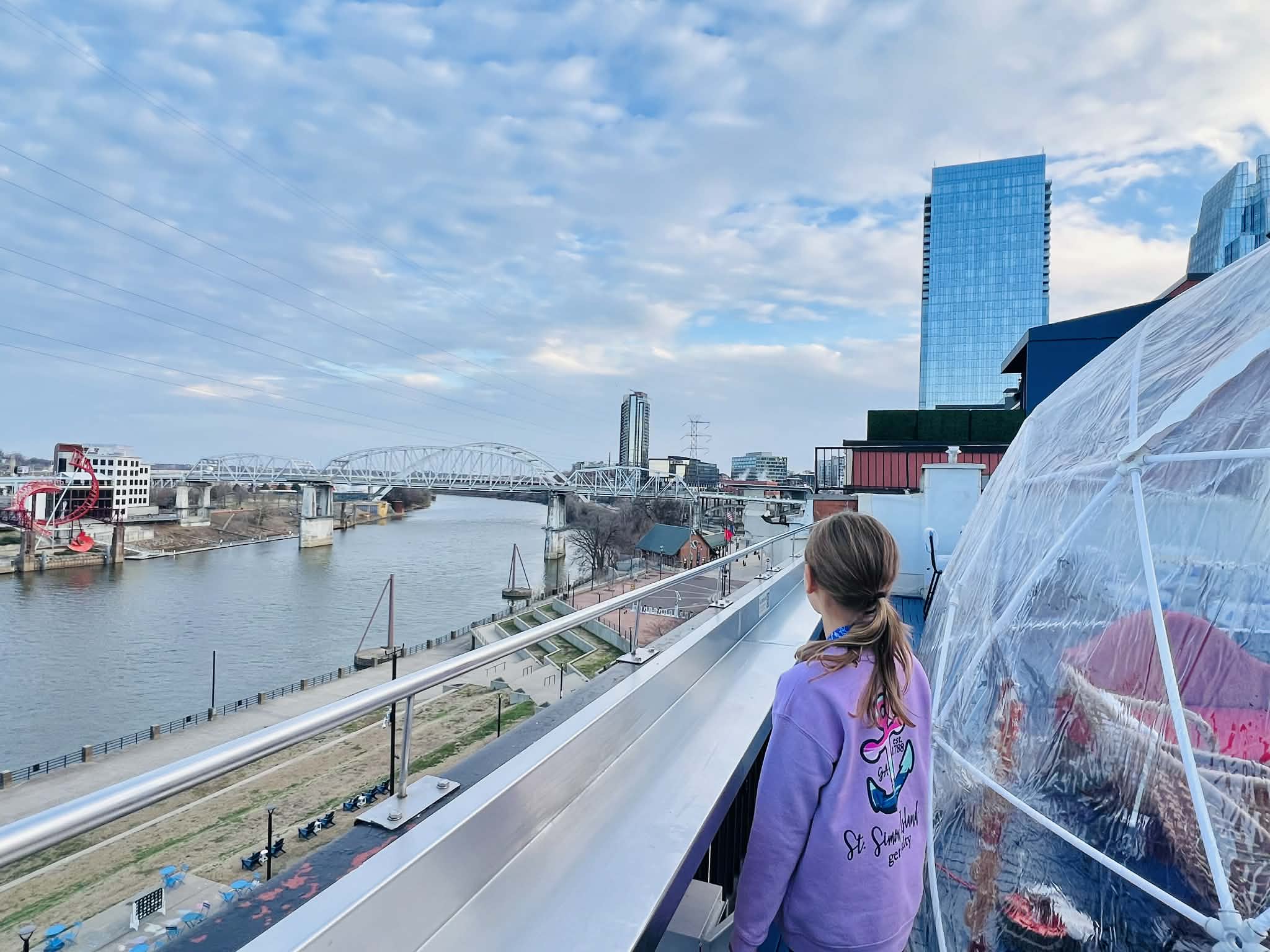 A little kid in downtown Nashville looking at the river from a rooftop.