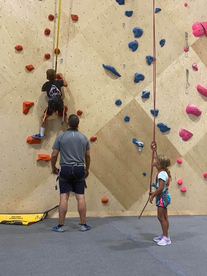 A dad and his two kids rock climbing at The Climb in Nashville.