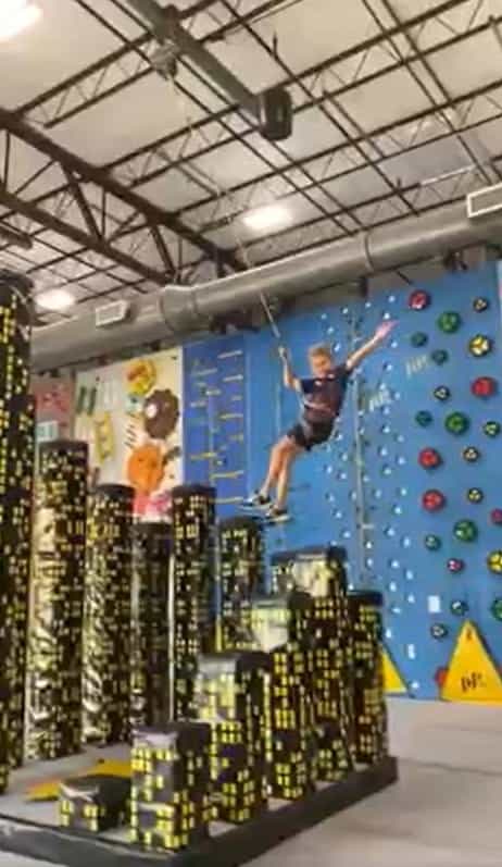 A boy on a belay rope flying through the air at The Climb rock climbing center in Nashville.