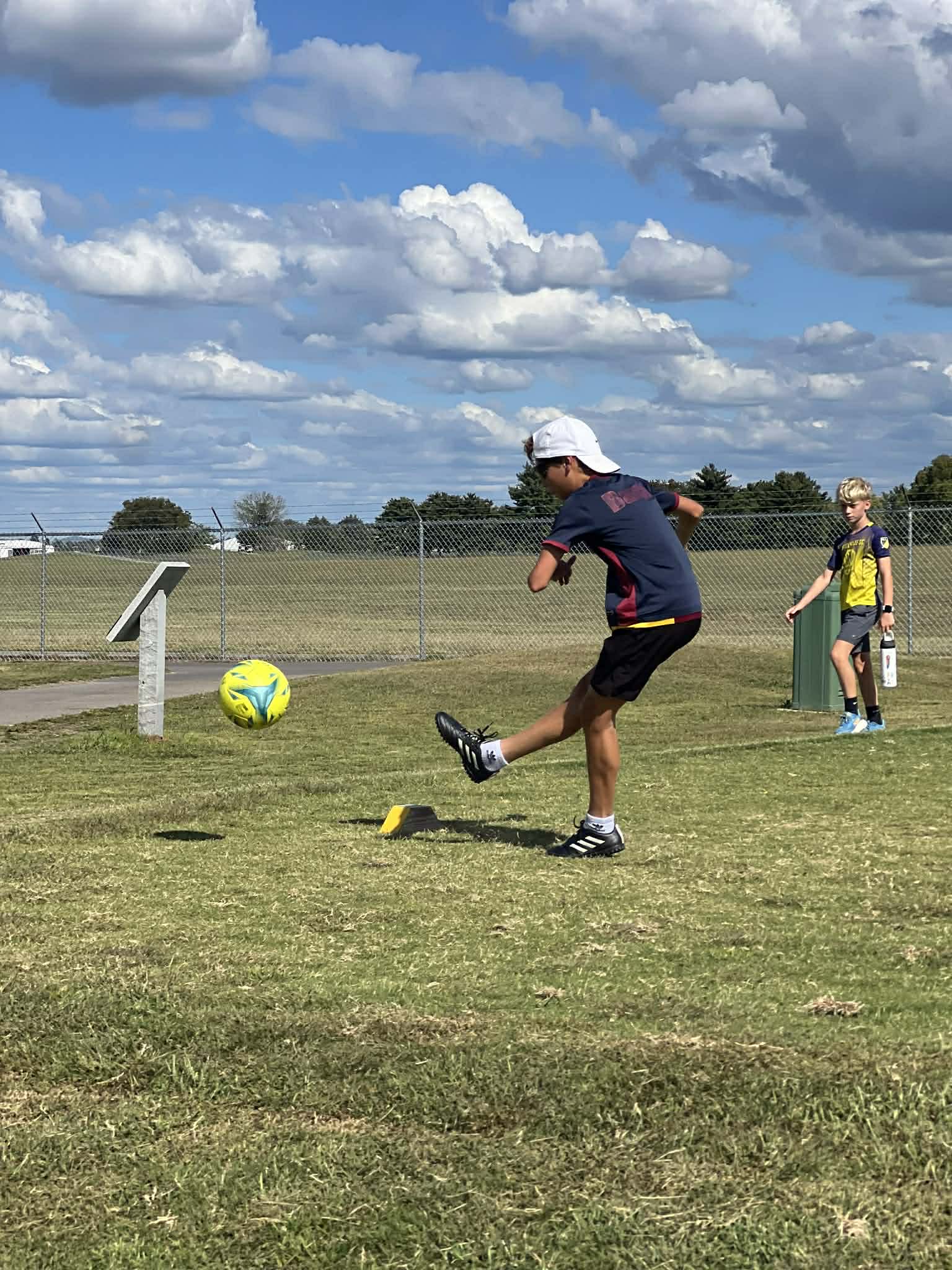 A teenage boy kicking a soccer ball while playing soccer golf.
