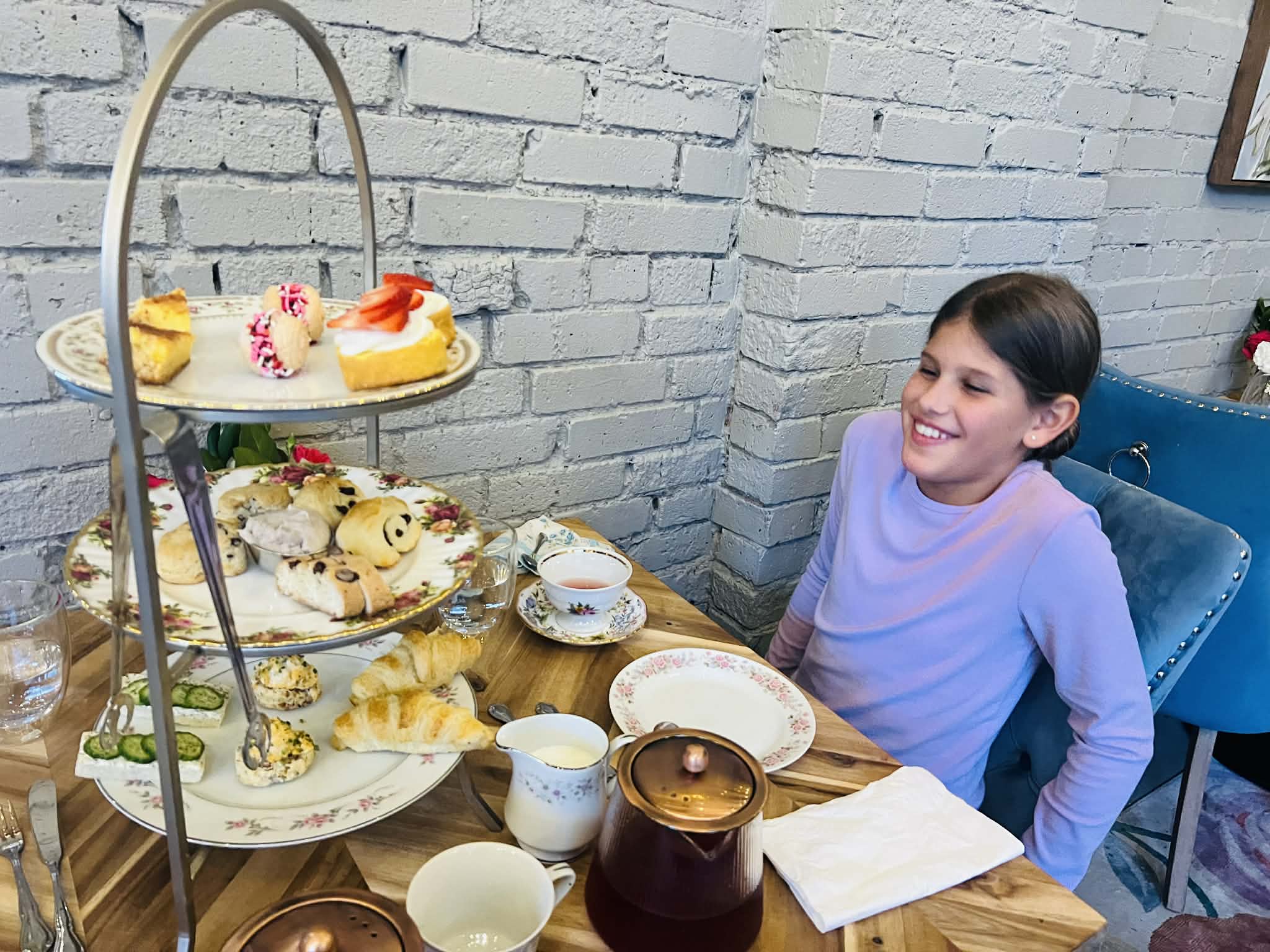 A little girl so happy to have all of the pastries in front of her at the tea shop.